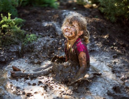 Photo of child jumping in mud 